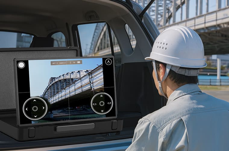 アタッシュケース型 AndroidタブレットPC PAP-270を橋桁付近で、ドローンの空撮映像確認に活用しているイメージ。